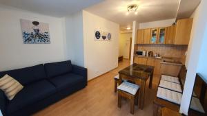 a living room with a blue couch and a kitchen at Apartmán TATRAN Jarka in Donovaly