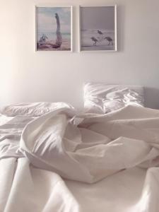 a bed with white sheets and two pictures on the wall at Volta Superior Studios in Avlemonas