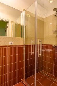 a glass shower in a bathroom with brown tiles at Admirala nams in Liepāja