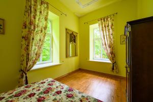 1 dormitorio con paredes amarillas, 2 ventanas y 1 cama en Admirala nams, en Liepāja