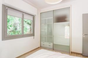 Homz AH19 Psychiko Apartment في أثينا: غرفة نوم مع خزانة زجاجية ونافذة