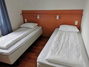 2 Betten in einem kleinen Zimmer mit weißer Bettwäsche in der Unterkunft Bjugn Hotell in Botngard