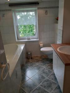 ein Badezimmer mit Badewanne und Toilette und einem Fenster in der Unterkunft Familienfreundliche Ferienwohnung in Zschorlau + 9 Fotos