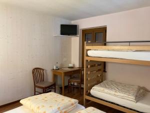 a room with two bunk beds and a desk with a chair at Hotel Ristorante Baldi in Fiesso
