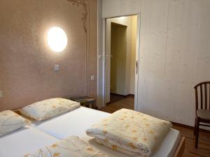 een slaapkamer met 2 bedden en een lampje aan de muur bij Hotel Ristorante Baldi in Fiesso