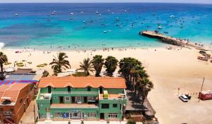 een strand met een groen huis en mensen in het water bij Mister Barracuda in Santa Maria