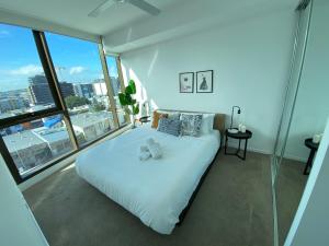 uma grande cama branca num quarto com janelas grandes em Perfect short term stay in Brissy Cozy & Relax em Brisbane