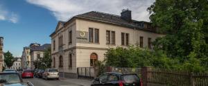 un edificio blanco con coches estacionados frente a él en Parkhotel Plauen, en Plauen