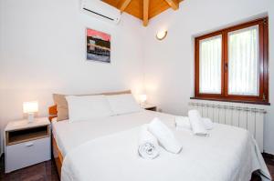 a white bedroom with a large white bed with white pillows at Apartments Carmelo in Rovinj