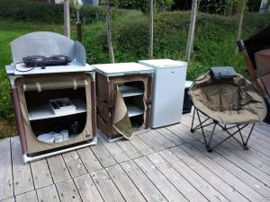 a grill and a refrigerator and a chair on a deck at Camping les Tournesols in Sillé-le-Guillaume