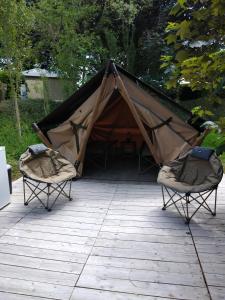 a tent and two chairs on a patio at Camping les Tournesols in Sillé-le-Guillaume
