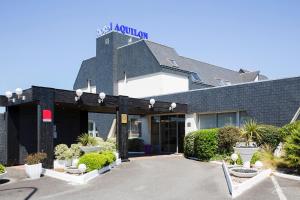 a hotel building with a sign on top of it at The Originals Boutique, Hôtel Aquilon, Saint-Nazaire (Inter-Hotel) in Saint-Nazaire