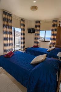 2 camas en un dormitorio con sábanas azules y ventanas en Sunset Seaview Apartments, en Marsalforn