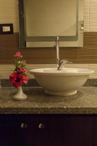 Elite Residence & Aqua Park في العين السخنة: منضدة حمام مع حوض و مزهرية مع الزهور