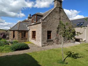 an old stone house with a tree in front of it at Chapel of Barras B&B in Stonehaven