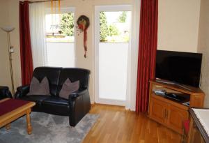 a living room with a black leather chair and a television at Ferienwohnung Am Sundern in Tecklenburg