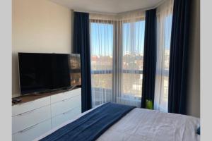 a bedroom with a flat screen tv and a large window at Studio 13 in Varna City