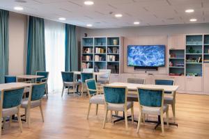 une salle de conférence avec des tables, des chaises et une télévision dans l'établissement DOMITYS LES PAGELLES, à Toulouse