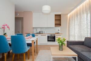 eine Küche und ein Wohnzimmer mit einem Tisch und blauen Stühlen in der Unterkunft ShortStayPoland Apartamenty in Warschau