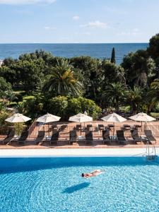 a beach area with a pool, chairs, and a beach umbrella at Don Carlos Resort & Spa in Marbella
