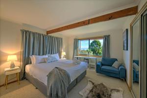 een slaapkamer met een groot bed en een blauwe stoel bij Zenith in Coles Bay