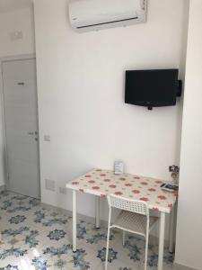 einen Tisch mit 2 Stühlen und einen TV an der Wand in der Unterkunft Albergo Oasi in Neapel