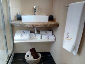 a bathroom with a sink and towels on a shelf at O Refúgio das Buracas in Condeixa a Nova