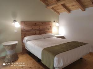 a bedroom with a large bed with a wooden headboard at Finca La Calancha in Cuerva