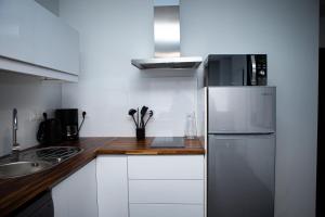 uma cozinha com armários brancos e um frigorífico de aço inoxidável em Balcons sur Seine - Vernon Giverny em Vernon