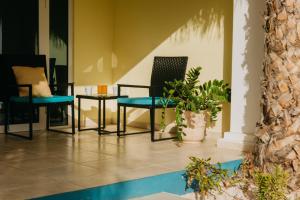 un vestíbulo con sillas, mesas y plantas en Aqua Viva Suites en Kralendijk