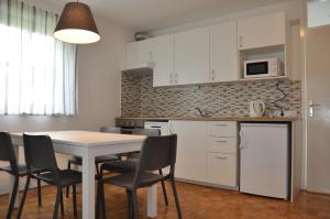 cocina con armarios blancos, mesa y sillas en Apartma Julija Hiška 59, en Čatež ob Savi