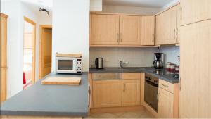 - une cuisine avec des placards en bois et un four micro-ondes dans l'établissement Les Pins - Apt 11 - BO Immobilier, à Châtel