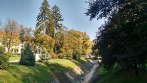 a garden with a river and trees and a building at Sobe Lara in Gradačac