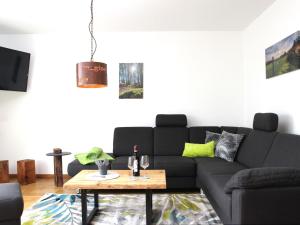 a living room with a black couch and a table at Chalet Am Scheidt in Medebach