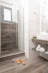 a bathroom with a shower and two shoes on the floor at Almare Seaside Studios & Suites - Sarti Sithonia in Sarti