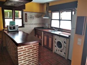 a kitchen with a sink and a washing machine at Casa El Pilpayu in Po