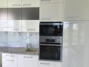 a kitchen with white cabinets and black appliances at Balatonparti Gyöngyszem in Keszthely