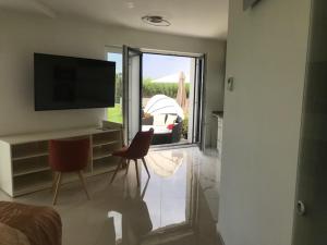 a living room with a television and a couch and chairs at Balatonparti Gyöngyszem in Keszthely