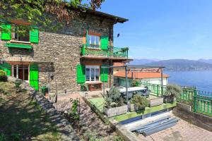 a building with green doors and windows next to the water at La Sorgente Bed & Breakfast in Baveno