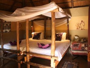 a bedroom with a wooden canopy bed with white sheets at Discovery Bed and Breakfast in Maun