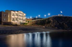 un edificio su una collina vicino a un corpo d'acqua di Almare Seaside Studios & Suites - Sarti Sithonia a Sárti