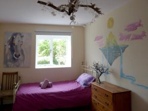 a bedroom with a purple bed and a window at Stable Cottage "The Unicorn Stable" in Yelverton