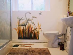 a bathroom with a toilet with a painting on the wall at Stable Cottage "The Unicorn Stable" in Yelverton +6 photos