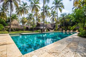 a swimming pool in front of a resort with palm trees at Gitana del Mar Beach Retreat in Buritaca
