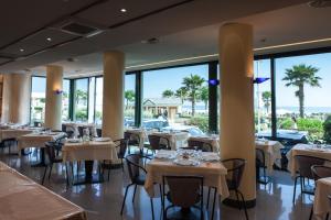 a restaurant with tables and chairs and large windows at Hotel Brig in Riccione