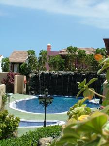 a swimming pool with a waterfall in a resort at Aparthotel El Cerrito in Los Cancajos