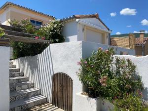 una casa blanca con una valla, escaleras y flores en La Salamandre de l Olivier - le Palmier en Aubignosc