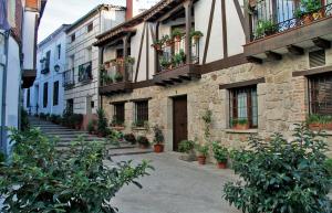 un edificio in pietra con piante in vaso sui balconi di Albergue El Encuentro a Villanueva de la Vera
