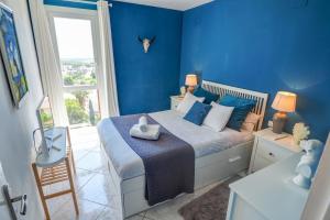 a blue bedroom with a bed with blue walls and a window at Palma Fiesta Apartment by Hello Homes Sitges in Sant Pere de Ribes