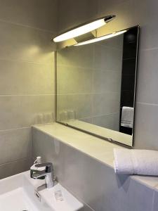 a bathroom with a mirror and a sink at Hotel Colbert in Tours